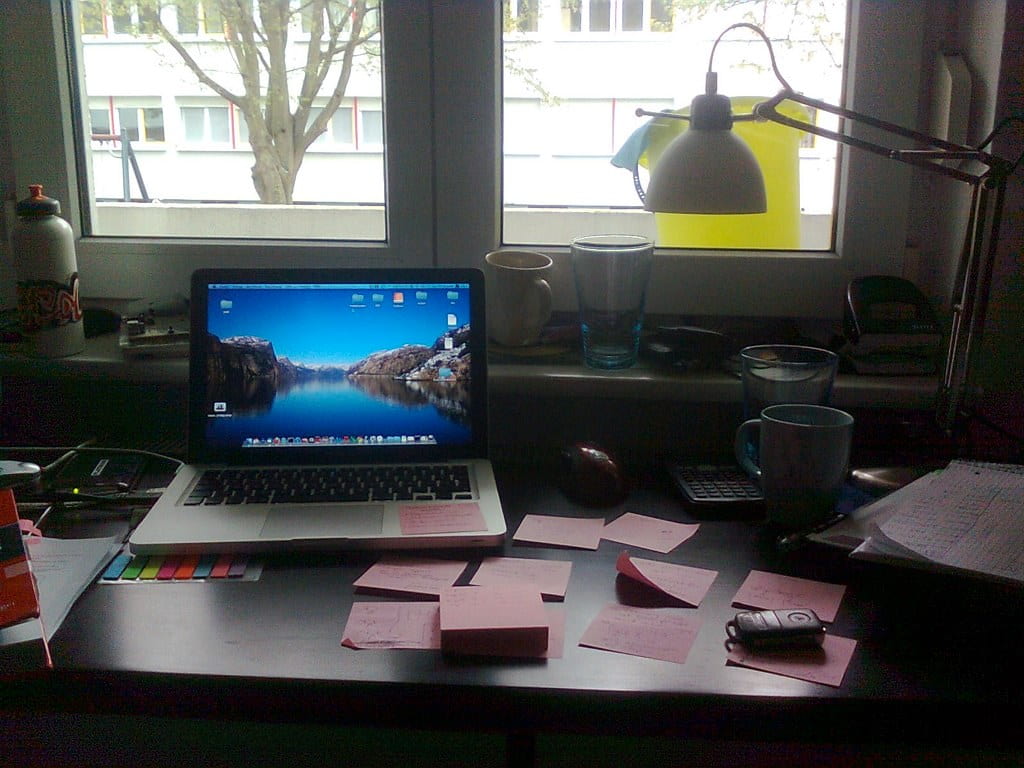 Desk with laptop, sticky notes and lamp